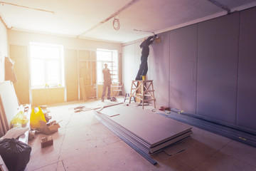 Wall Mural - Workers are installing plasterboard (drywall) for gypsum walls in apartment is under construction, remodeling, renovation, extension, restoration and reconstruction.