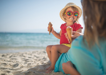 Mother and doughter eating ice cream on sandy beach