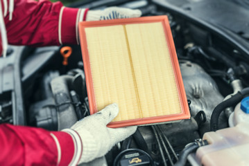 The auto mechanic replaces the car's air filter.