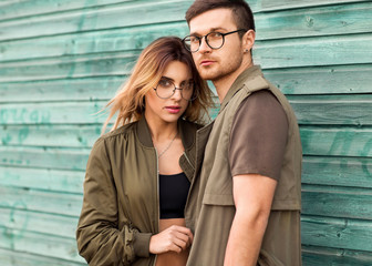 fashion couple standing posing near green wooden wall