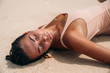 Portrait of a gorgeous girl with a sexy body on the beach with white sand. Young woman in swimsuit sunbathing on a summer vacation abroad. Charming model on a desert island.
