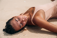 Portrait Of A Gorgeous Girl With A Sexy Body On The Beach With White Sand. Young Woman In Swimsuit Sunbathing On A Summer Vacation Abroad. Charming Model On A Desert Island.