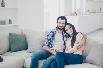 Wall Mural - Portrait of stylish trendy couple spending time together indoor, in flat, apartment sitting on sofa looking at camera. True feelings affection idyllic harmony concept