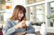 © successphoto - Young asian woman with beautiful smile with friends enjoying coffee together in a coffee shop,Smiling woman in a good mood with cup of coffee sitting in cafe while relaxing in cafe during free time