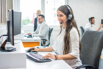 Wall Mural - Young smiling operator woman agent with headsets working in call center.