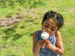 Young girl enjoys eating an ice cream in the park