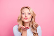 © deagreez - Portrait of pretty friendly girl in casual outfit with modern hairdo blowing air kiss with pout lips palm at camera isolated on pink background. Pomade lipstick concept