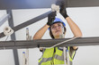 © Westend61 - Young female electrician installing lamp
