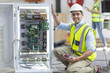 © Westend61 - Portrait of smiling technician working on a box with circuit boards