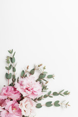 Wall Mural - Pastel flowers and eucalyptus leaves on white table top view. Flat lay style.