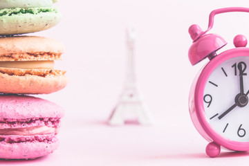 Wall Mural - Close up of multicolored macarons and alarm clock with Eiffel Tower in the background.