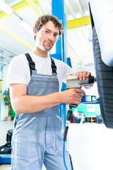 Wall Mural - Male mechanic changing car tire or tyre in workshop