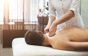 Woman massaging male shoulders and back