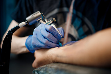 tattoo process machine close-up. master prepares for procedure of drawing