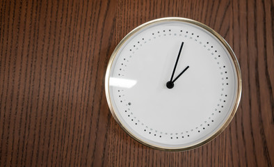 Modern white and gold clock on wooden background