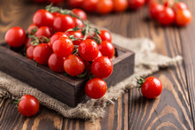 Small Red Cherry Tomatoes On Rustic Background. Cherry Tomatoes On The Vine