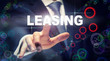 © Duncan Andison - A hand selecting a Leasing business concept on a clear screen with a colorful blurred background.