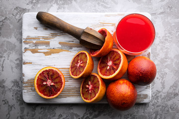 Wall Mural - Red sicilian orange pieces and squeezer on wooden board closeup. Healthy diet vitamin concept. Food photography