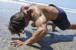 Strong man doing intense bear crawl beach workout