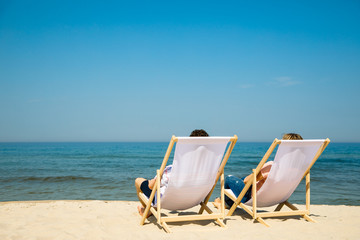 Wall Mural - Woman and man relaxing on beach