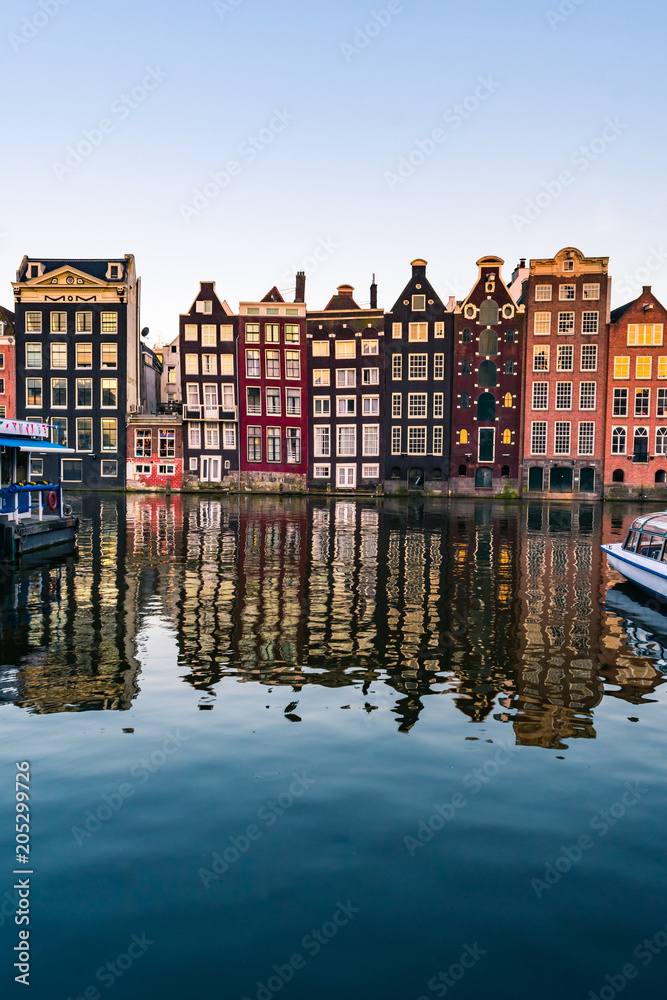 View of colorful facades of typical Amsterdam houses reflecting in the Amstel river canal in Amsterdam during sunset - obrazy, fototapety, plakaty 