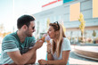 © Nebojsa - Happy young couple sitting in front of a mall and eating ice cream