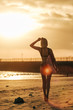 © LIGHTFIELD STUDIOS - back view of girl posing with surfboard on beach at sunset with back light