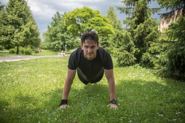 young man doing push-ups in park 