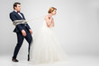 bride in wedding dress pulling groom bound with rope, isolated on grey, feminism concept