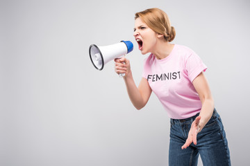 woman in pink feminist t-shirt yelling at megaphone, isolated on grey