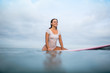 © LIGHTFIELD STUDIOS - smiling attractive woman in white wet swimsuit sitting on surfboard in ocean during summer vacation