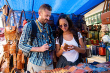 Couple Tourists Looking At Leather Products In Shopping Stall
