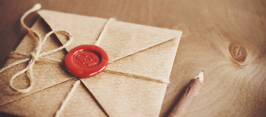 love letter in a craft envelope with a sealing wax seal in the form of a heart on a wooden backgroun