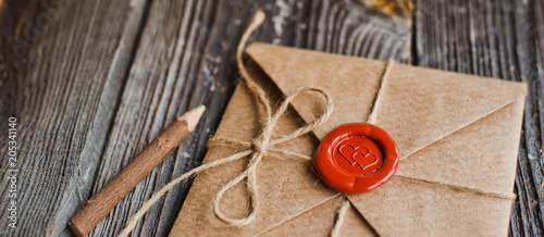 Fotomural love letter in a craft envelope with a sealing wax seal in the form of a heart on a wooden background