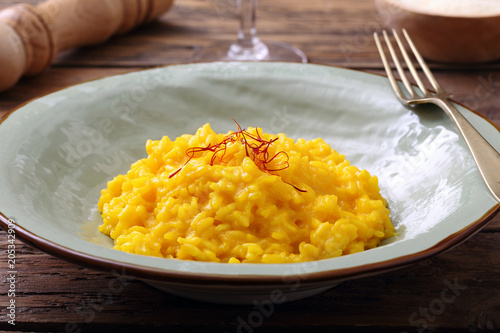 Cuadros en Lienzo risotto allo zafferano tradizionale italiano su sfondo tavolo di cucina rustico