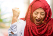 Young arab woman wearing hijab happy and excited expressing winning gesture. Successful and celebrating victory, triumphant