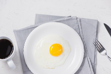 Wall Mural - Top view of white dish with fried egg on white background.