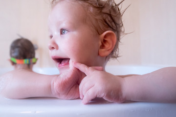 Two funny boys in rainbow glasses for swimming in large bathroom. Children are happy together. Water with foam for a bath. Aromatic shampoo, soap for children. Blond hair in foam. Personal hygiene.