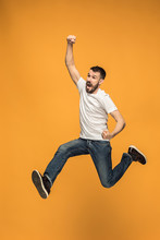 Freedom In Moving. Handsome Young Man Jumping Against Orange Background