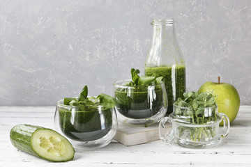 Wall Mural - Close up of homemade green smoothie made from fresh spinach, peas, cucumber and apple on white wooden background