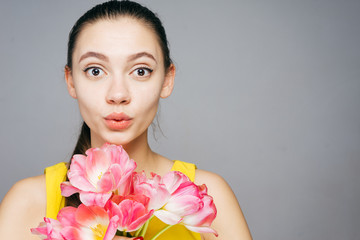 cute surprised young girl holding fragrant spring flowers and looking at the camera