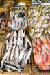 Various types of raw fish are displayed on the table for sale in the market. The fish is mixed with ice to preserve its freshness.