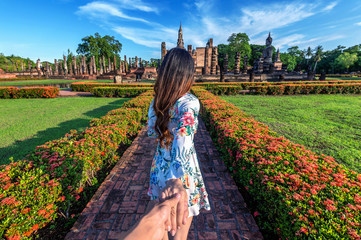 Wall Mural - Woman holding man's hand and leading him to Wat Mahathat Temple in the precinct of Sukhothai Historical Park, Wat Mahathat Temple is UNESCO World Heritage Site, Thailand.