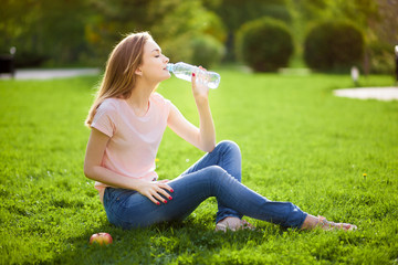 girl sits on the lawn and drinks water