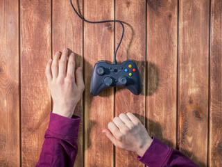 Wall Mural - hands with video game gamepad controller on a wooden table