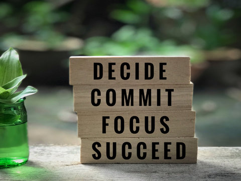 Motivational and inspirational quote - ‘Decide, commit, focus, succeed’ written on wooden blocks. With vintage styled background.