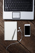 Office wooden desk with pen, notepad, coffee cup, smartphone and earphones. Top view