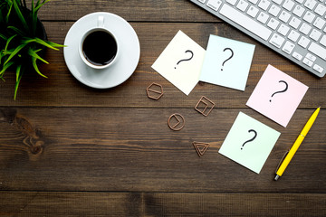 Poster - Question mark on sticky notes on office desk on dark wooden background top view copy space. FAQ concept. Working with clients. Troubles in work.