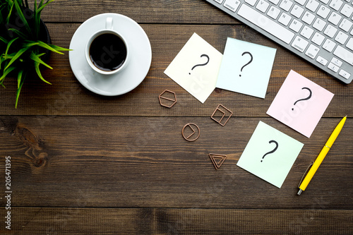 Foto Question mark on sticky notes on office desk on dark wooden background top view copy space