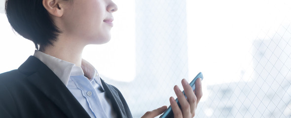 Young woman holding smart phone in the office.